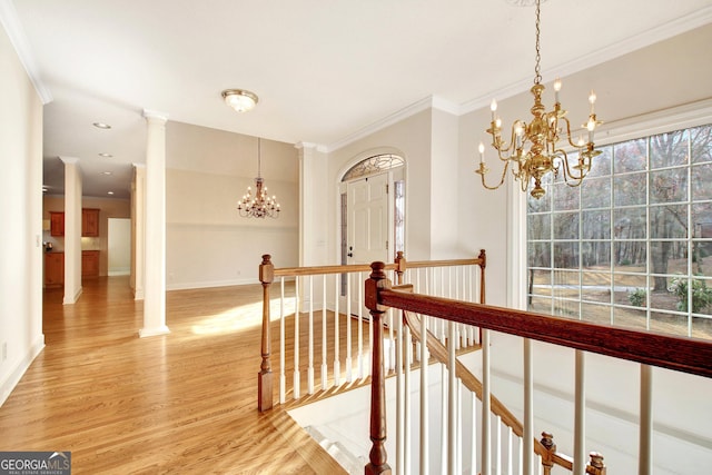 hallway featuring a chandelier, ornamental molding, wood finished floors, and an upstairs landing