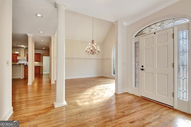 entryway with decorative columns, light wood-style floors, vaulted ceiling, a chandelier, and baseboards