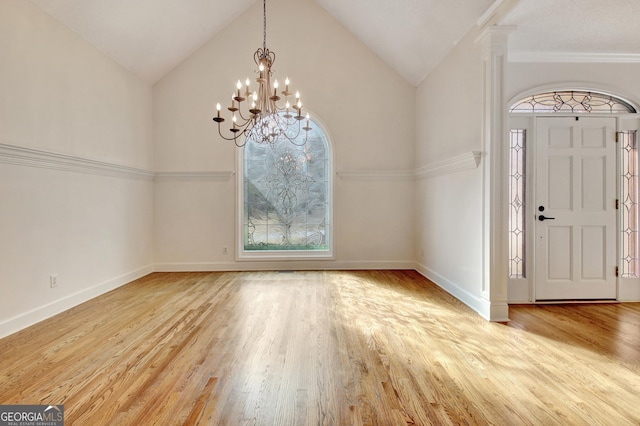 foyer with light wood-type flooring, decorative columns, baseboards, and vaulted ceiling