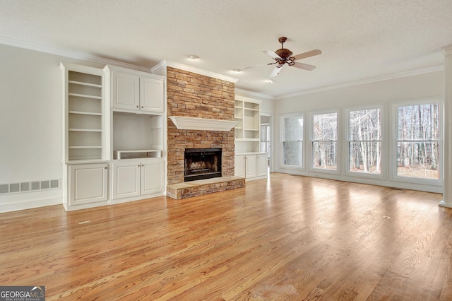 unfurnished living room with light wood-style flooring, visible vents, a textured ceiling, and ornamental molding