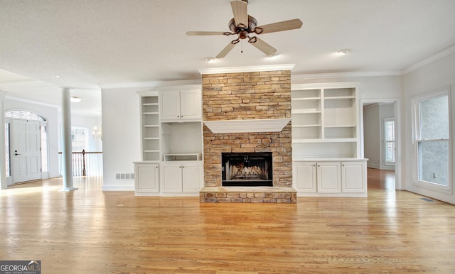 unfurnished living room with light wood-style floors, built in shelves, visible vents, and ornamental molding