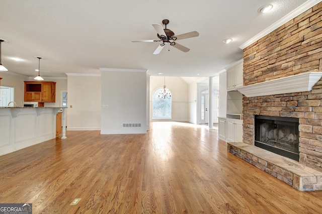 unfurnished living room with light wood finished floors, ceiling fan, visible vents, and ornamental molding