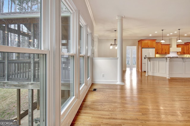 interior space with ornate columns, ornamental molding, and light wood-style floors