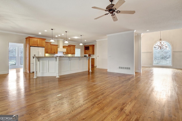 unfurnished living room featuring light wood-type flooring, visible vents, crown molding, and ceiling fan with notable chandelier