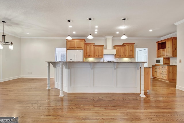 kitchen featuring hanging light fixtures, white appliances, a large island, and a kitchen bar