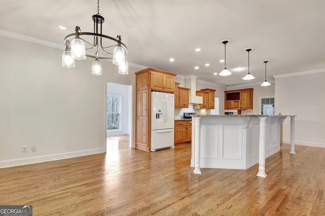 kitchen featuring light stone counters, pendant lighting, white refrigerator with ice dispenser, brown cabinets, and a kitchen breakfast bar