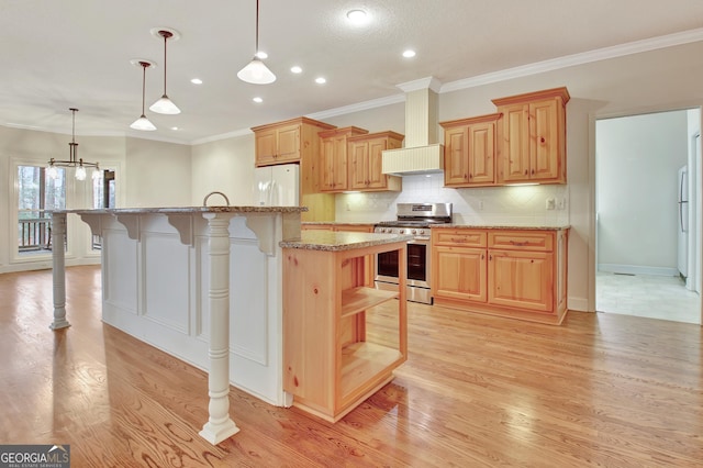 kitchen featuring stainless steel gas range oven, a breakfast bar, hanging light fixtures, light stone countertops, and a center island with sink