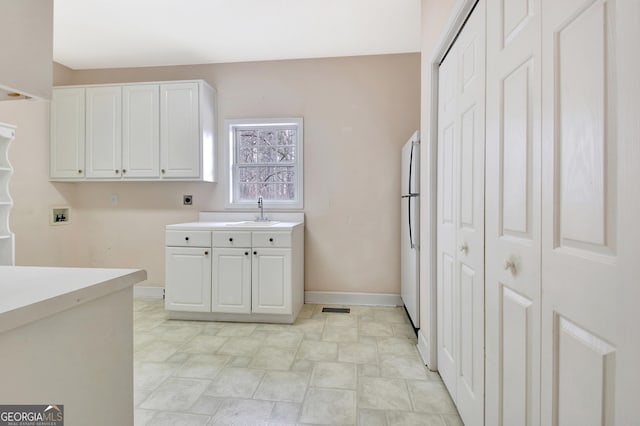 laundry room featuring hookup for an electric dryer, washer hookup, a sink, baseboards, and cabinet space