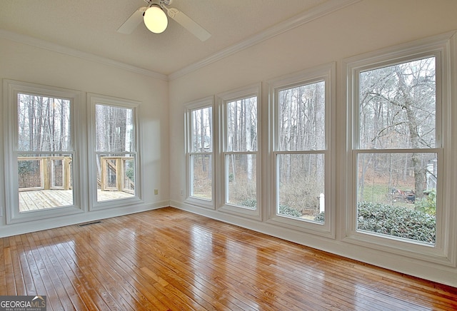 unfurnished sunroom with visible vents and a ceiling fan