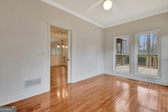 unfurnished room featuring light wood-style flooring, ceiling fan with notable chandelier, visible vents, baseboards, and ornamental molding