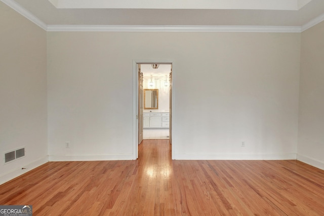 unfurnished room featuring ornamental molding, light wood finished floors, visible vents, and baseboards