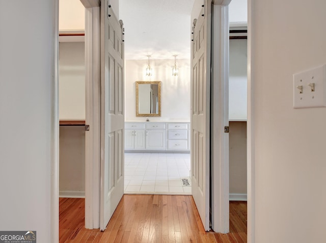 corridor featuring a barn door and light wood-type flooring