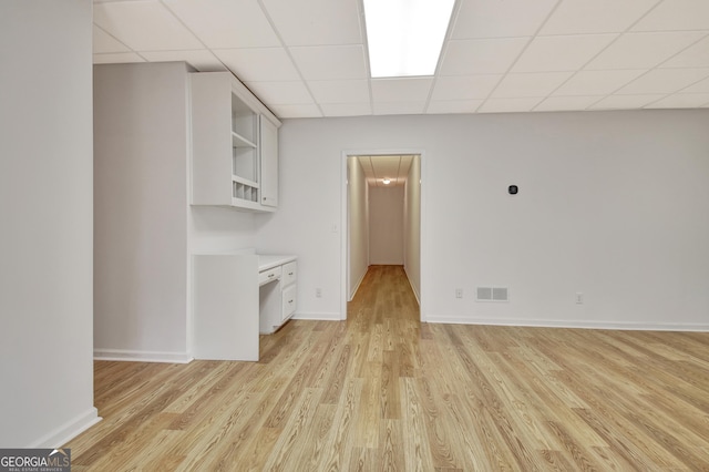 unfurnished room with light wood-style flooring, a drop ceiling, visible vents, and baseboards