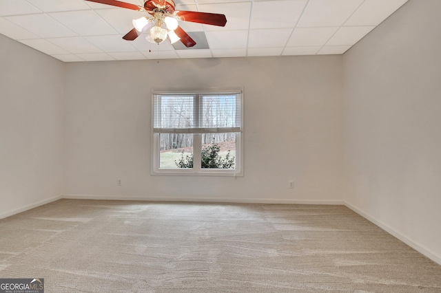 spare room featuring light carpet, ceiling fan, baseboards, and a drop ceiling