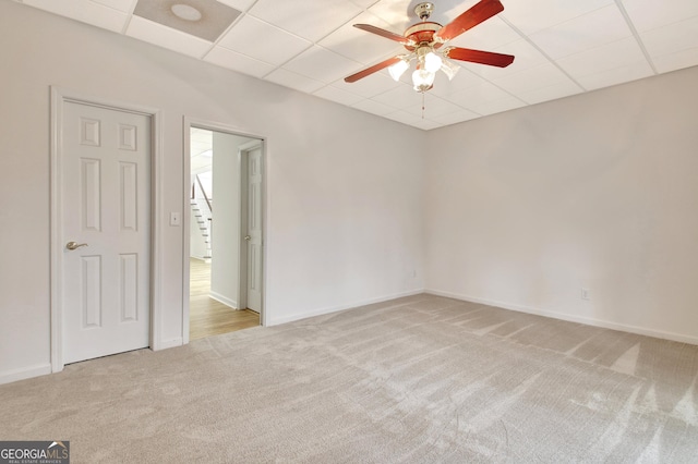 spare room featuring a ceiling fan, baseboards, light colored carpet, and a drop ceiling