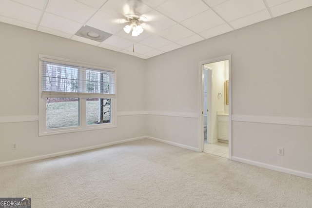 spare room featuring a paneled ceiling, ceiling fan, baseboards, and light colored carpet