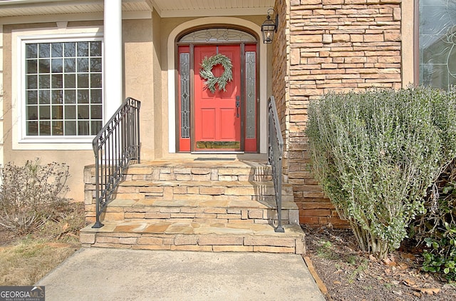 view of exterior entry featuring brick siding and stucco siding