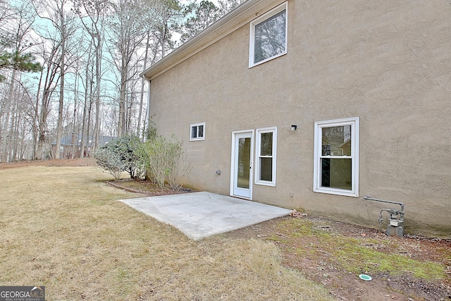 rear view of property with a yard, a patio, and stucco siding