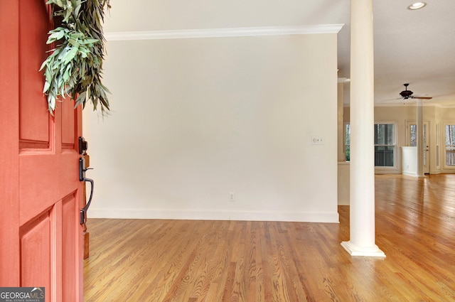 foyer with crown molding, decorative columns, light wood-style flooring, ceiling fan, and baseboards