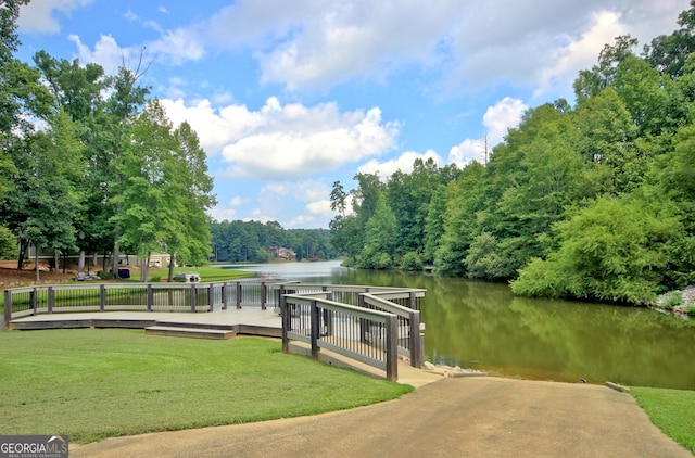 view of dock with a water view and a yard