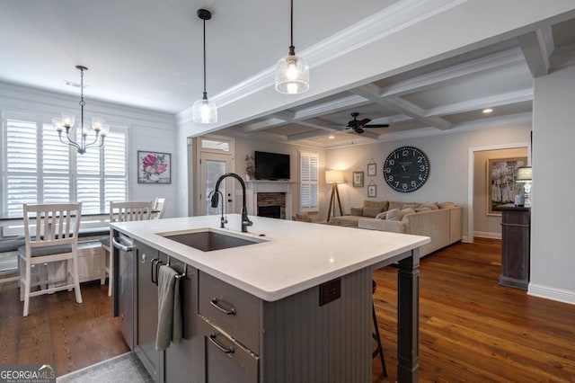 kitchen featuring light countertops, hanging light fixtures, open floor plan, a kitchen island with sink, and a sink