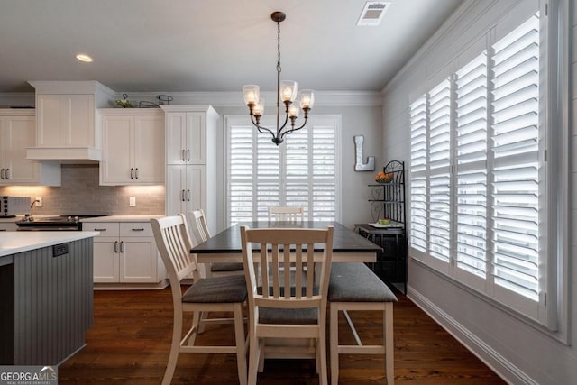 dining room with crown molding, dark wood finished floors, a wealth of natural light, visible vents, and an inviting chandelier