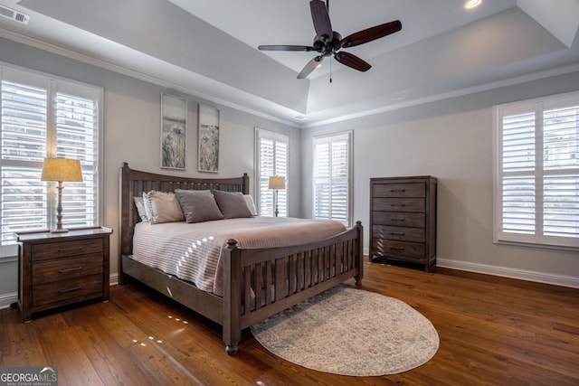 bedroom with baseboards, visible vents, a tray ceiling, and dark wood-type flooring