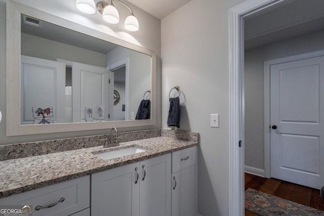 bathroom featuring visible vents, wood finished floors, vanity, and baseboards