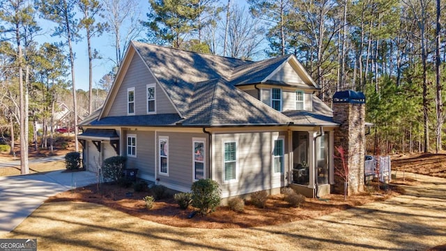 view of side of home with a garage, driveway, and a shingled roof