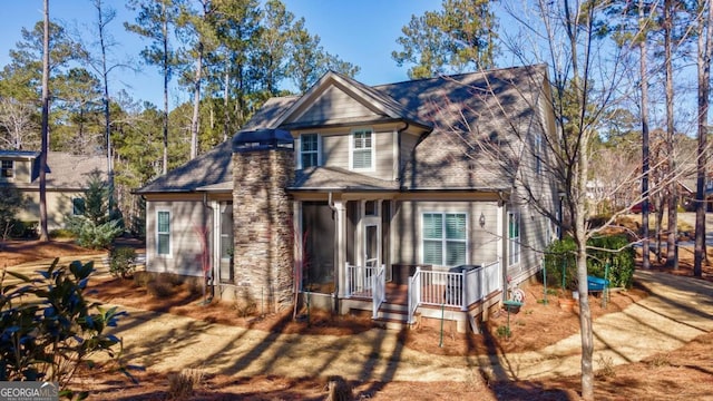 view of front of home featuring a shingled roof and dirt driveway