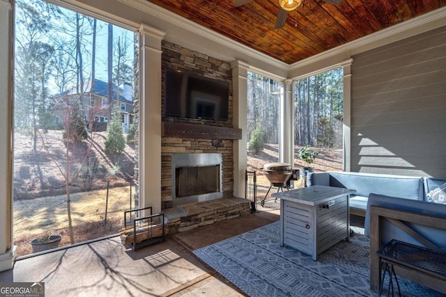 sunroom / solarium with wooden ceiling, an outdoor stone fireplace, and a ceiling fan