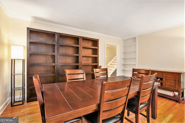 dining space featuring stairs, ornamental molding, light wood-style flooring, and baseboards