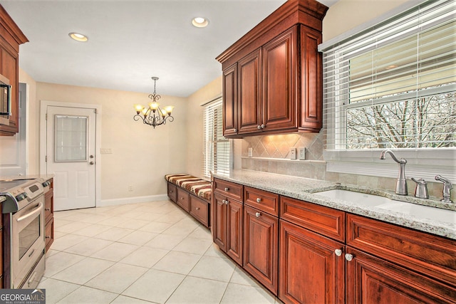 kitchen with stainless steel appliances, a sink, light stone counters, and decorative backsplash