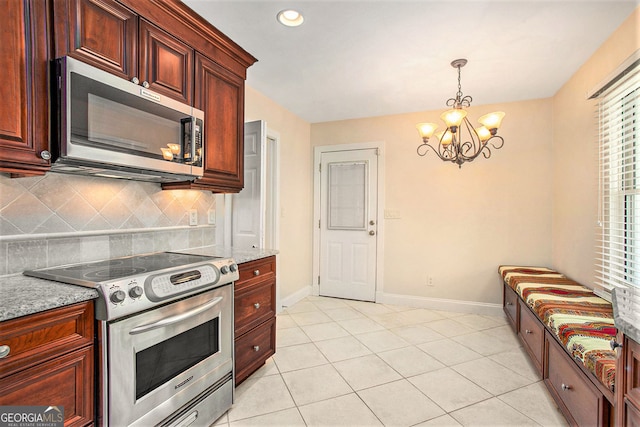 kitchen with decorative light fixtures, stainless steel appliances, tasteful backsplash, a chandelier, and baseboards