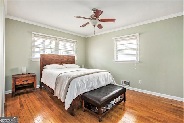 bedroom with hardwood / wood-style floors, visible vents, and crown molding