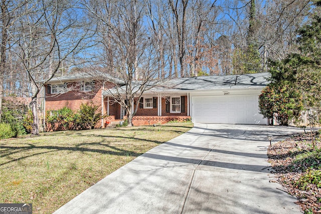 tri-level home featuring a garage, a front yard, concrete driveway, and brick siding