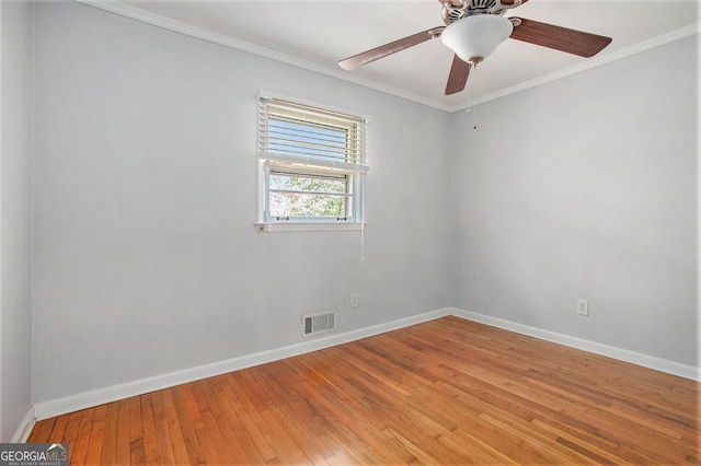 empty room featuring baseboards, visible vents, crown molding, and light wood finished floors