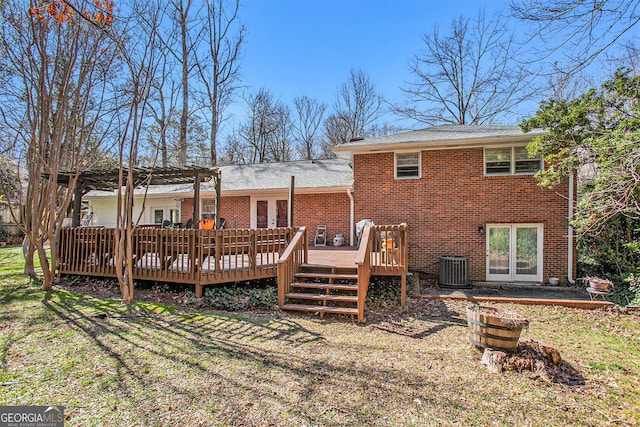 rear view of property with brick siding, a lawn, and a wooden deck