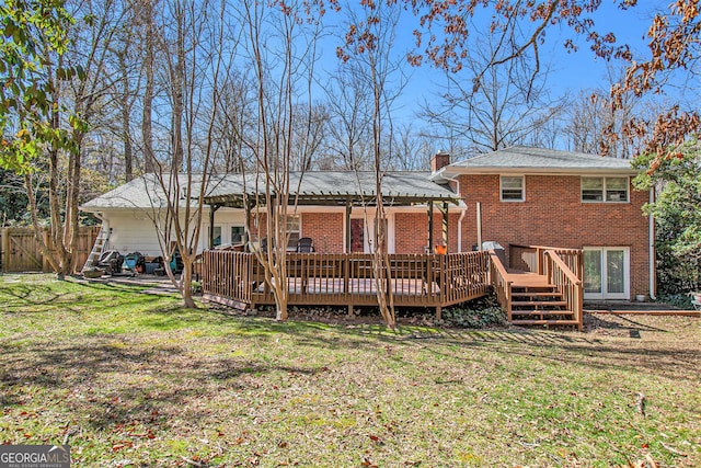 rear view of property with a chimney, fence, a deck, a yard, and brick siding