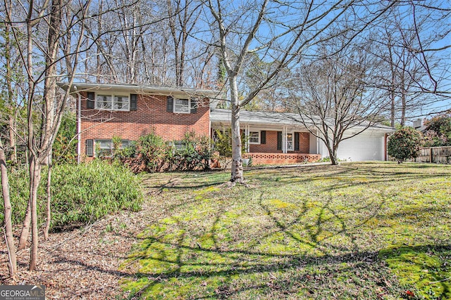 tri-level home featuring a garage, brick siding, and a front lawn