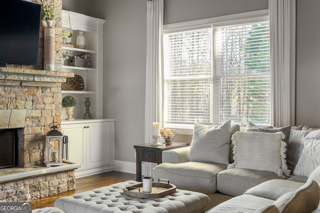 living room featuring a fireplace, baseboards, a wealth of natural light, and wood finished floors