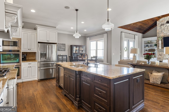 kitchen with dark brown cabinets, appliances with stainless steel finishes, white cabinets, and a sink