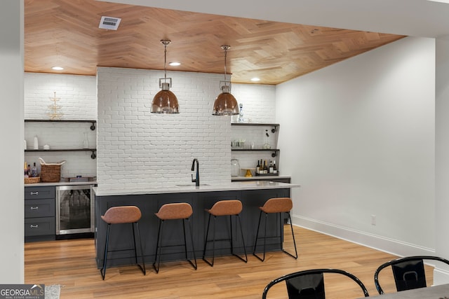 bar featuring light wood-style floors, wet bar, beverage cooler, and baseboards