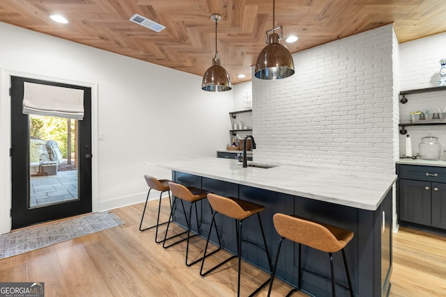 bar with brick wall, light wood finished floors, a sink, and visible vents