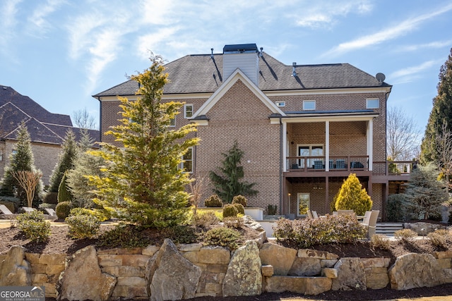 back of house with brick siding and a chimney