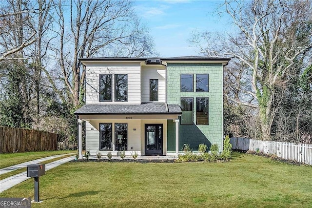 view of front of house with covered porch, fence, and a front lawn