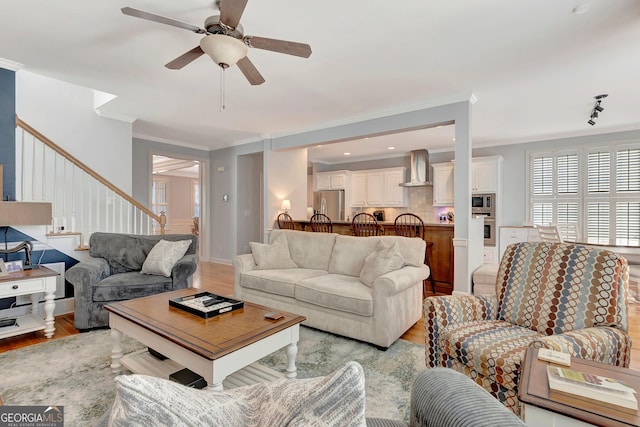 living room with crown molding, baseboards, a ceiling fan, and light wood-style floors