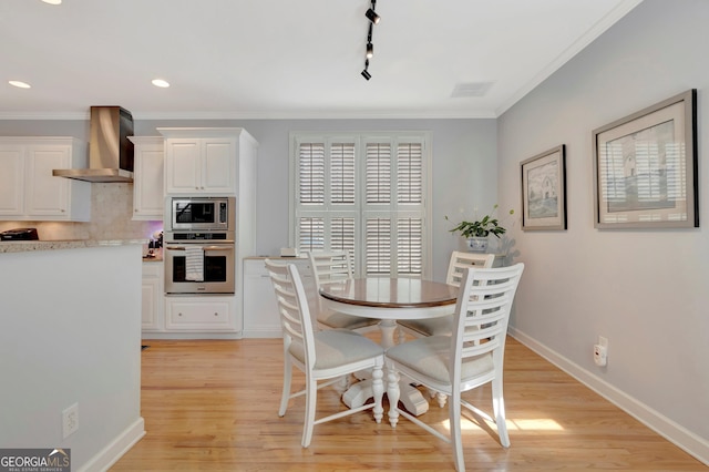 dining area featuring light wood finished floors, visible vents, baseboards, and crown molding