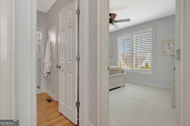 corridor featuring light wood-style floors, baseboards, and visible vents