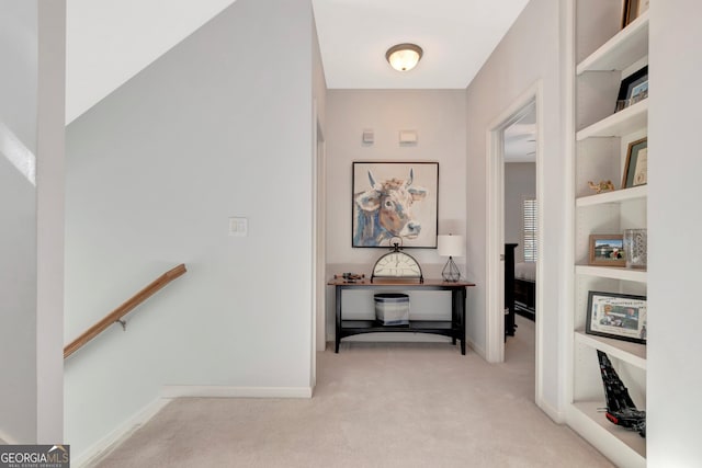 hall with baseboards, light colored carpet, and an upstairs landing